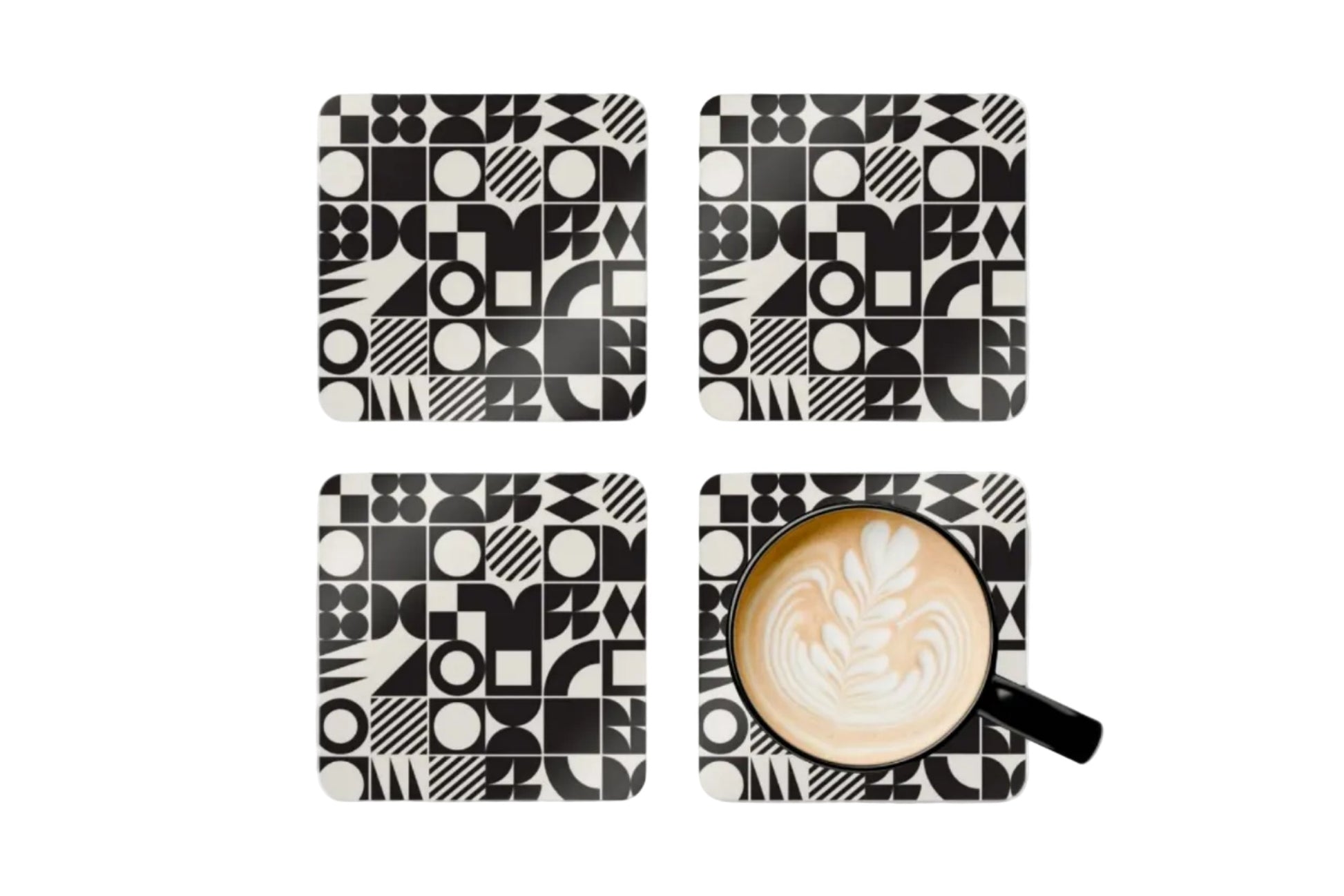Four black and white geometric patterned coasters with a cup of coffee on one coaster.