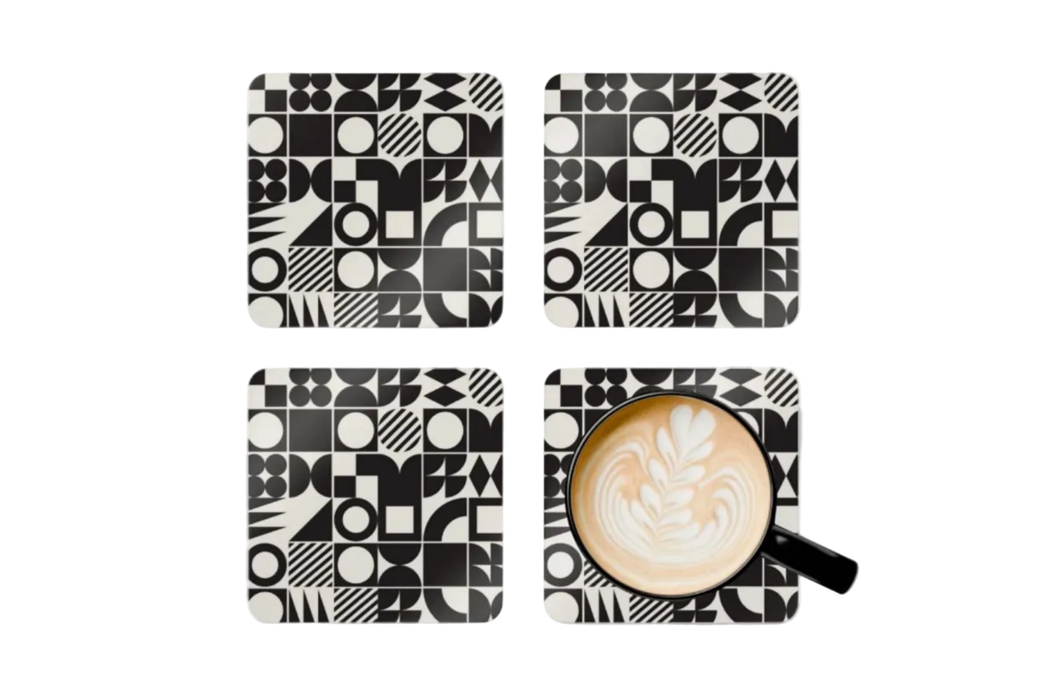 Four black and white geometric patterned coasters with a cup of coffee on one coaster.